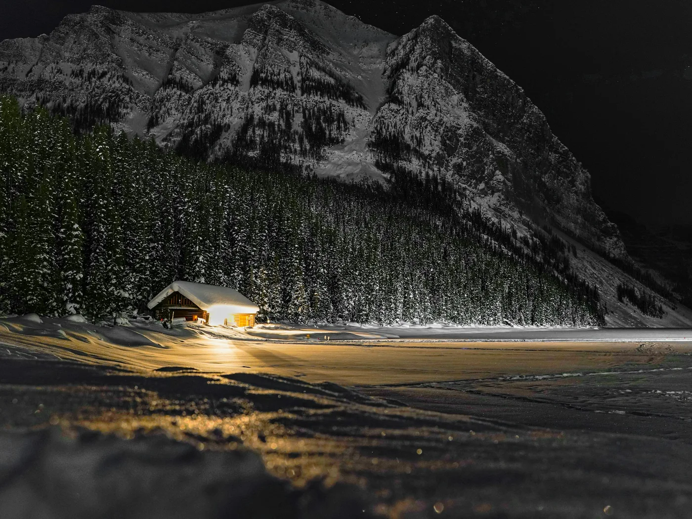 A lit boathouse at snowy Lake Louise after dark